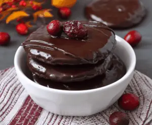 Delicious chocolate-covered cranberry sauce garnished with fresh cranberries and mint leaves, perfect for festive desserts