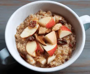 Delicious cinnamon apple quinoa breakfast bowl topped with fresh apple slices and a sprinkle of cinnamon, ready for a healthy morning start.
