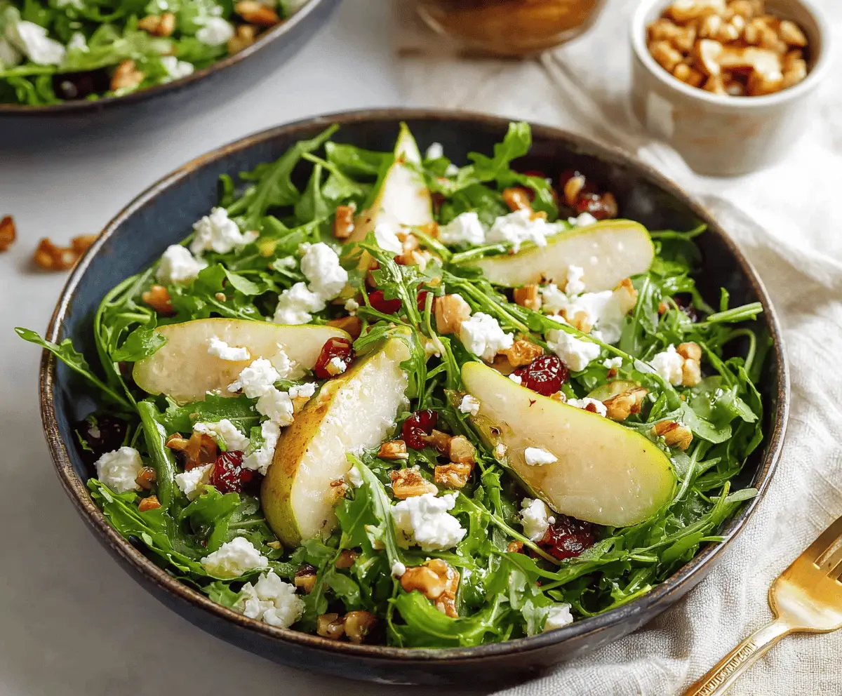 Fresh pear and arugula salad with walnuts and feta cheese, served in a white bowl, perfect for a healthy and delicious appetizer or light meal.