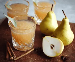 Refreshing Spiced Vanilla Pear Cocktail in a glass with garnished pear slice and cinnamon stick, perfect for fall and winter celebrations.