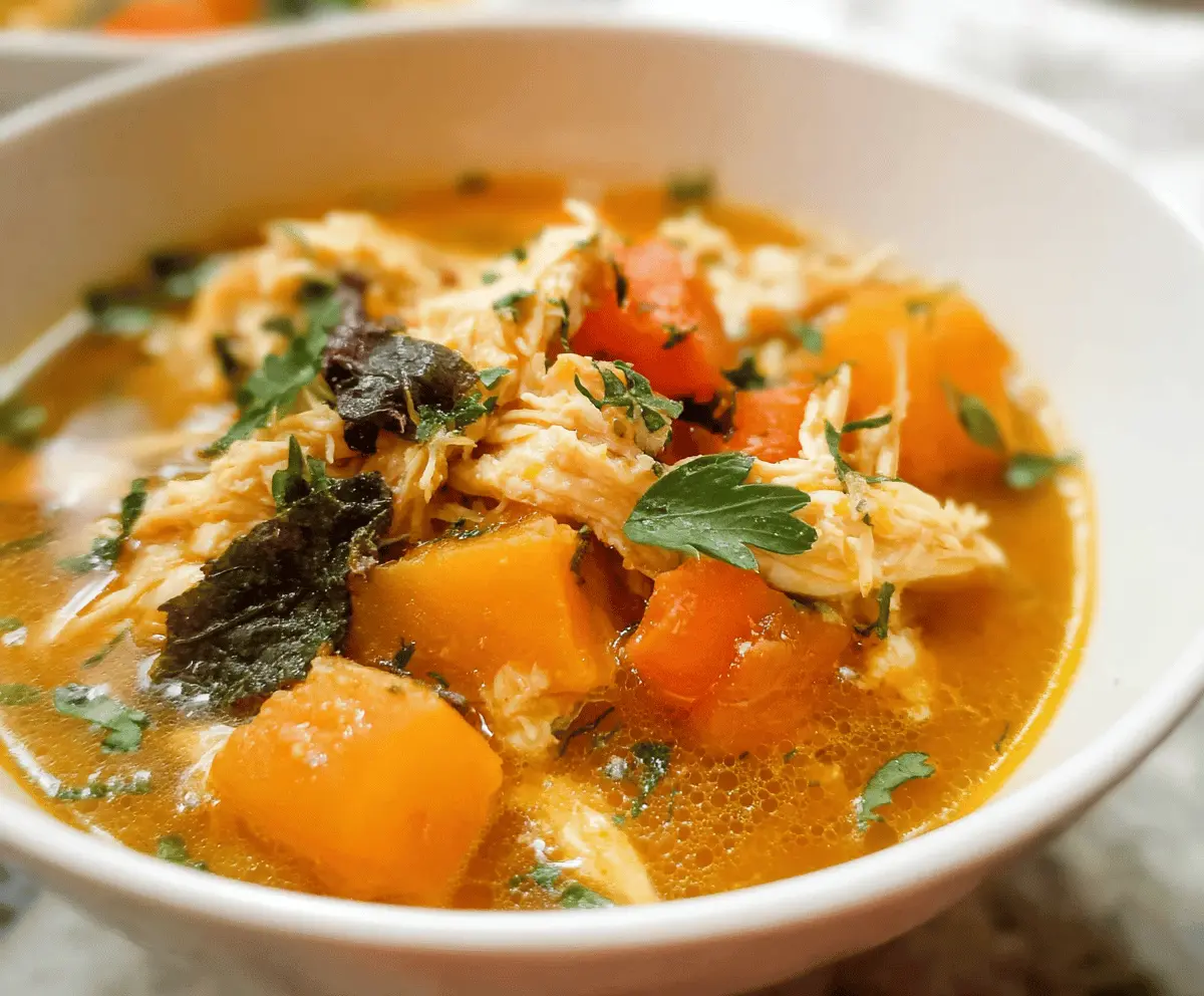Hearty slow cooker chicken and butternut squash stew in a bowl with fresh herbs and vegetables