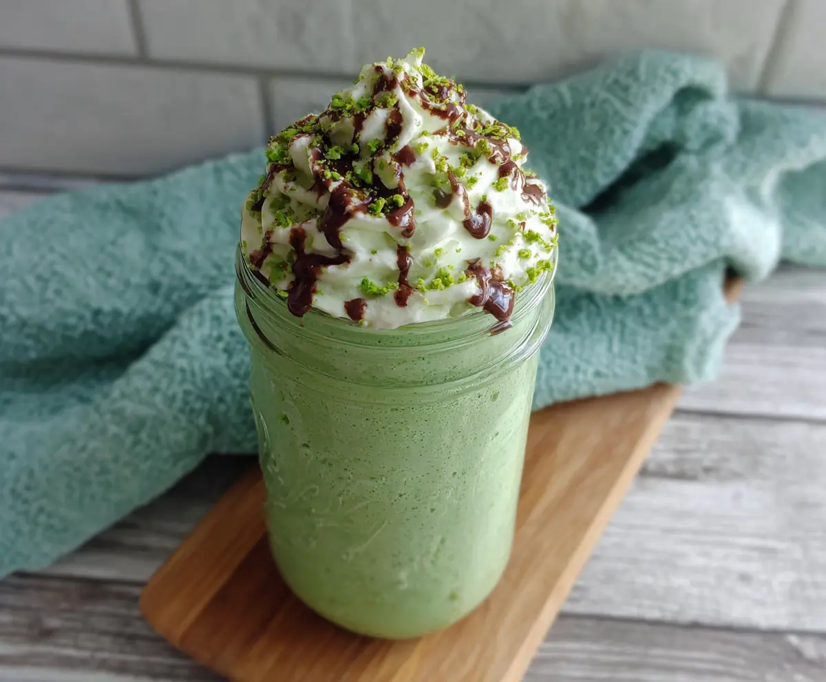 Healthy high protein shamrock shake in a glass garnished with mint for a festive St. Patrick's Day treat.