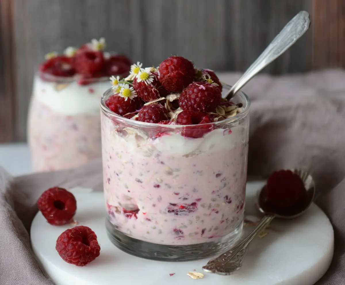 Creamy Raspberry Overnight Oats in a glass jar, topped with fresh raspberries and chia seeds.