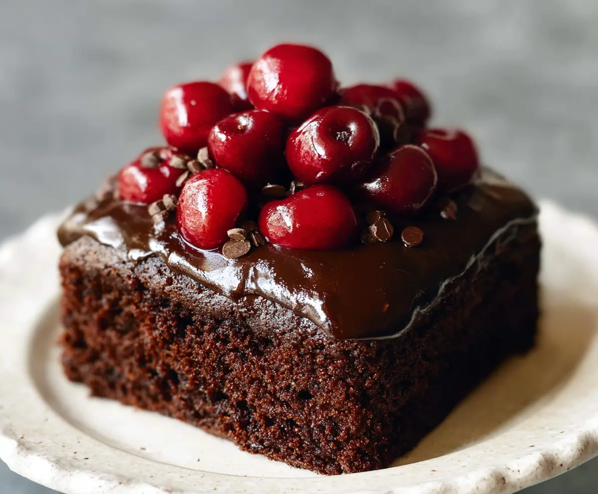 Delicious homemade chocolate cherry cake with rich frosting and fresh cherries on top.