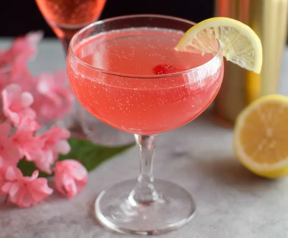 Elegant Pink Champagne Cocktail with a sparkling pink hue and a cherry garnish on a stylish glass.