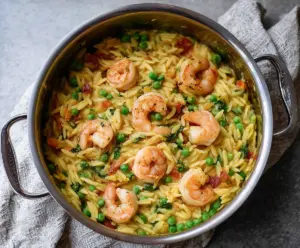 Delicious one pot pea and shrimp orzo dish garnished with herbs, perfect for a quick dinner.